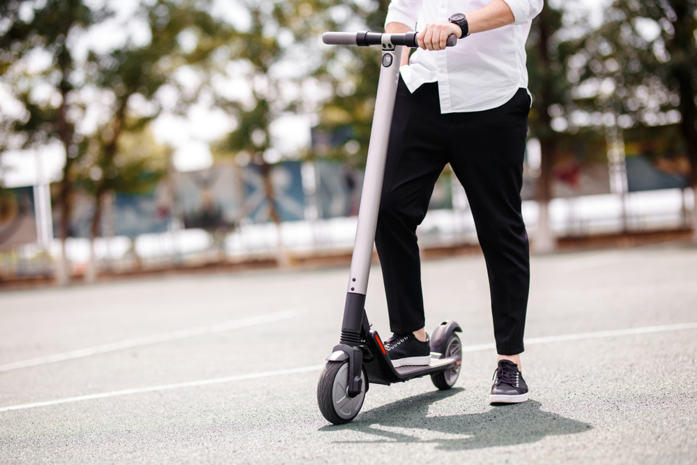 Ben av en man i snygg outfit står på elektrisk skoter på gatan